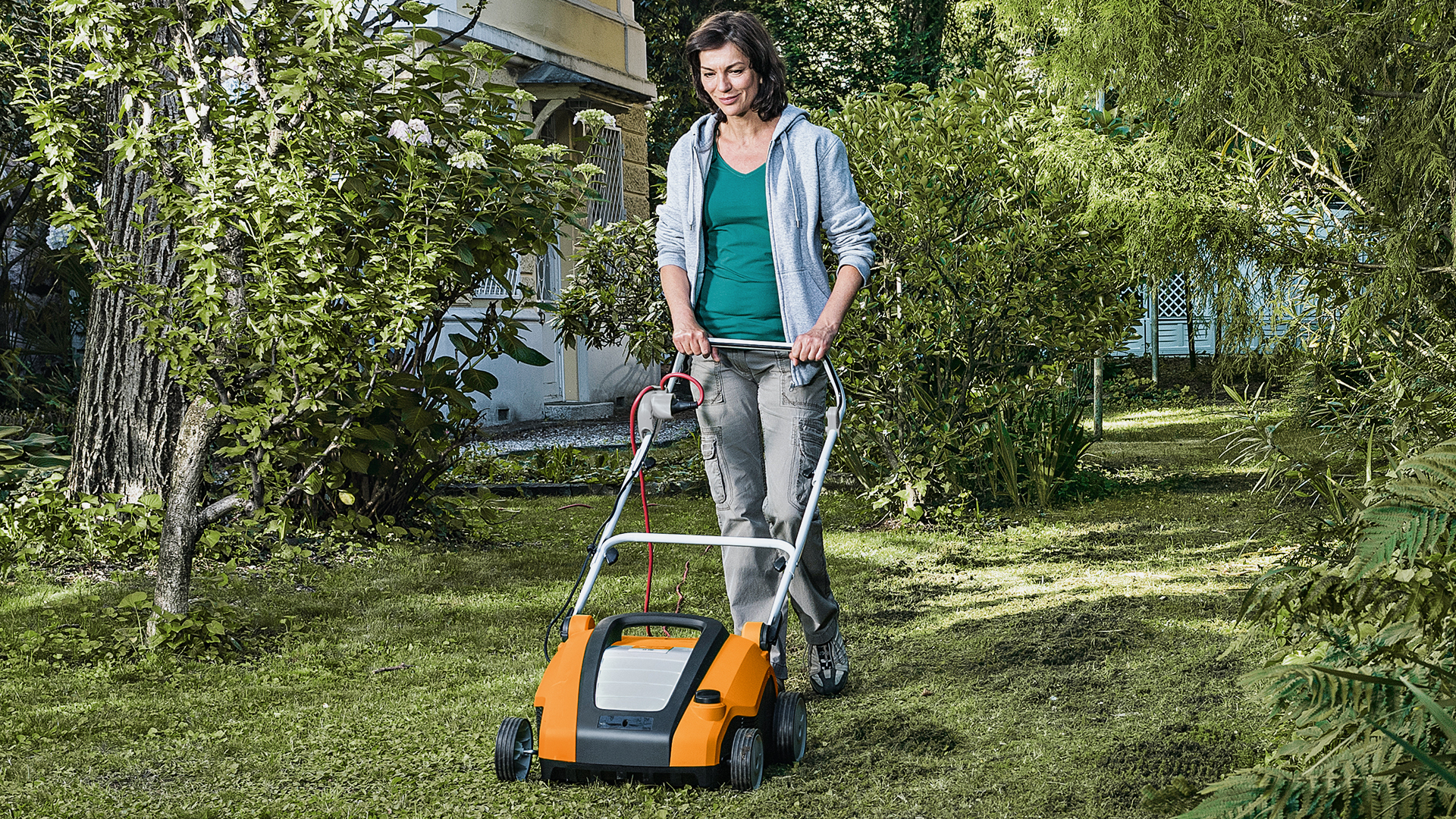 En kvinna arbetar i trädgården med en STIHL RLE 240 vertikalskärare