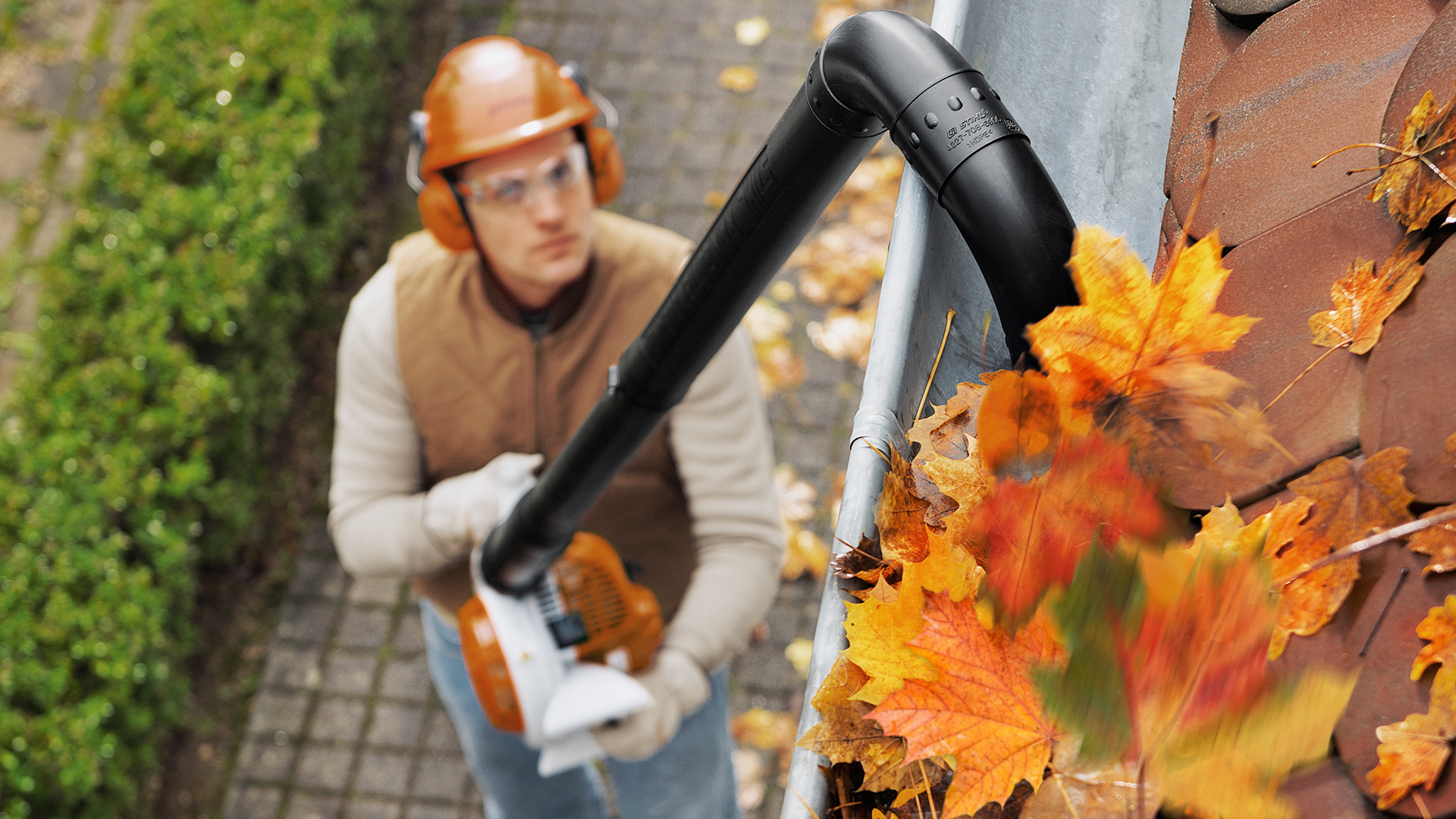 En man med STIHL BG 56 bensinlövblås rengör regnrännan