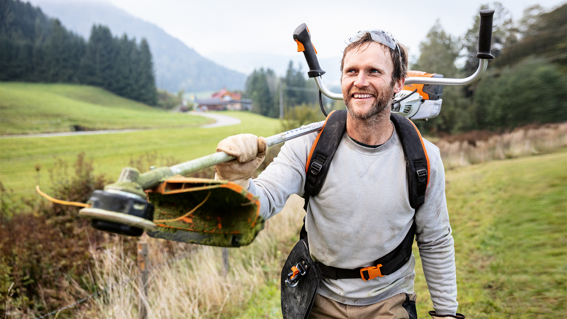 En man med STIHL grästrimmer och Advance PLUS universalsele på en äng