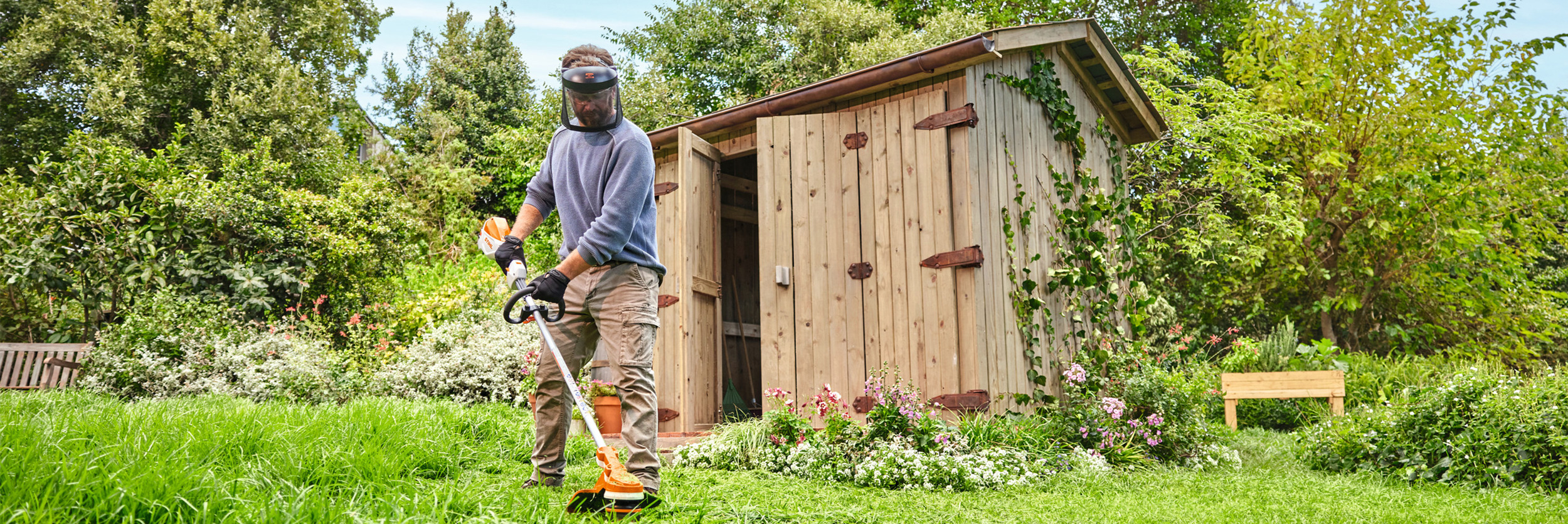  En man trimmar gräs med en STIHL FSA 70 R batteridriven röjsåg