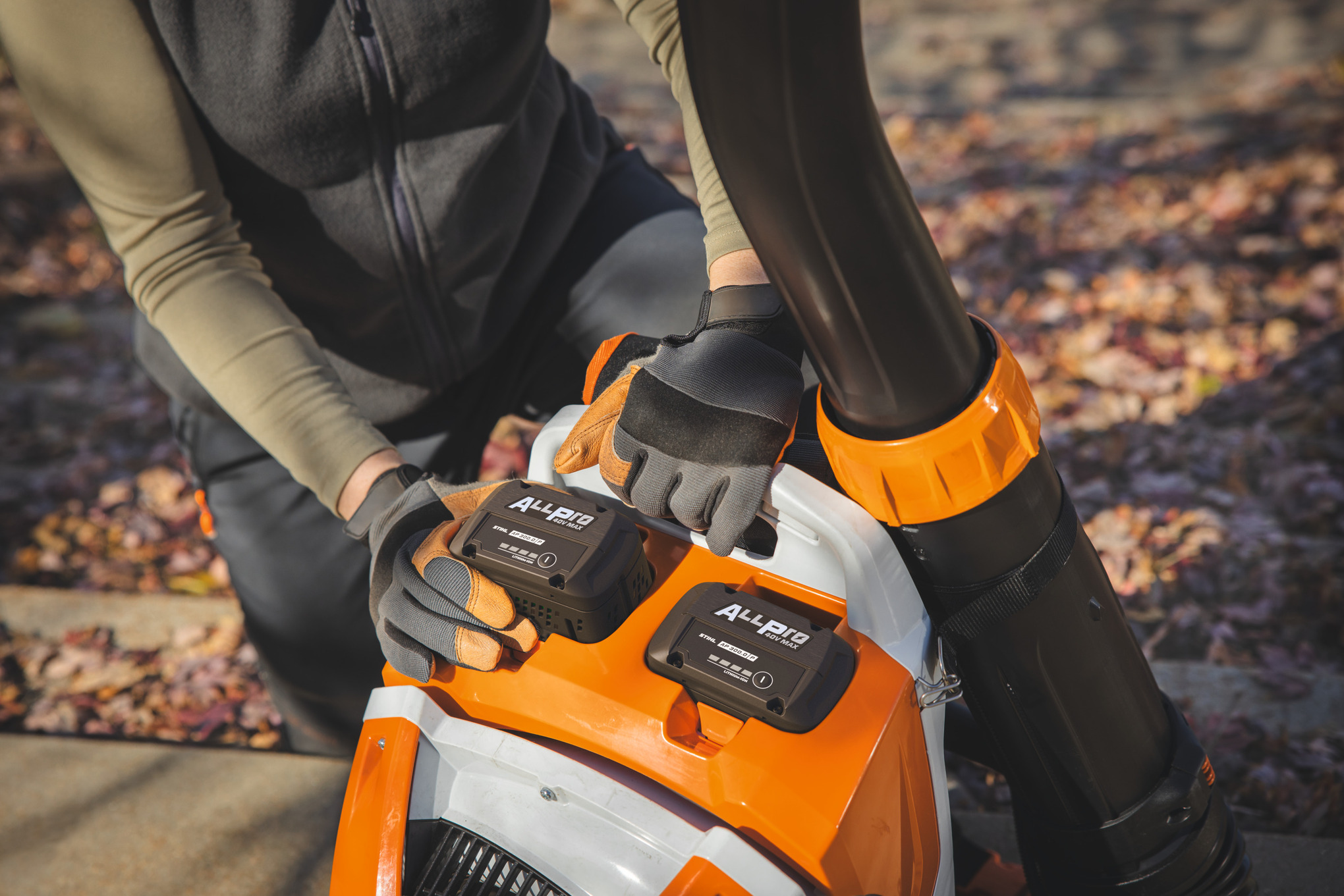 Ein professionella Landschaftsgärtner setzt den zweiten STIHL-Akku AP 300.0 P in das STIHL-Akku-Rucksackgebläse ein