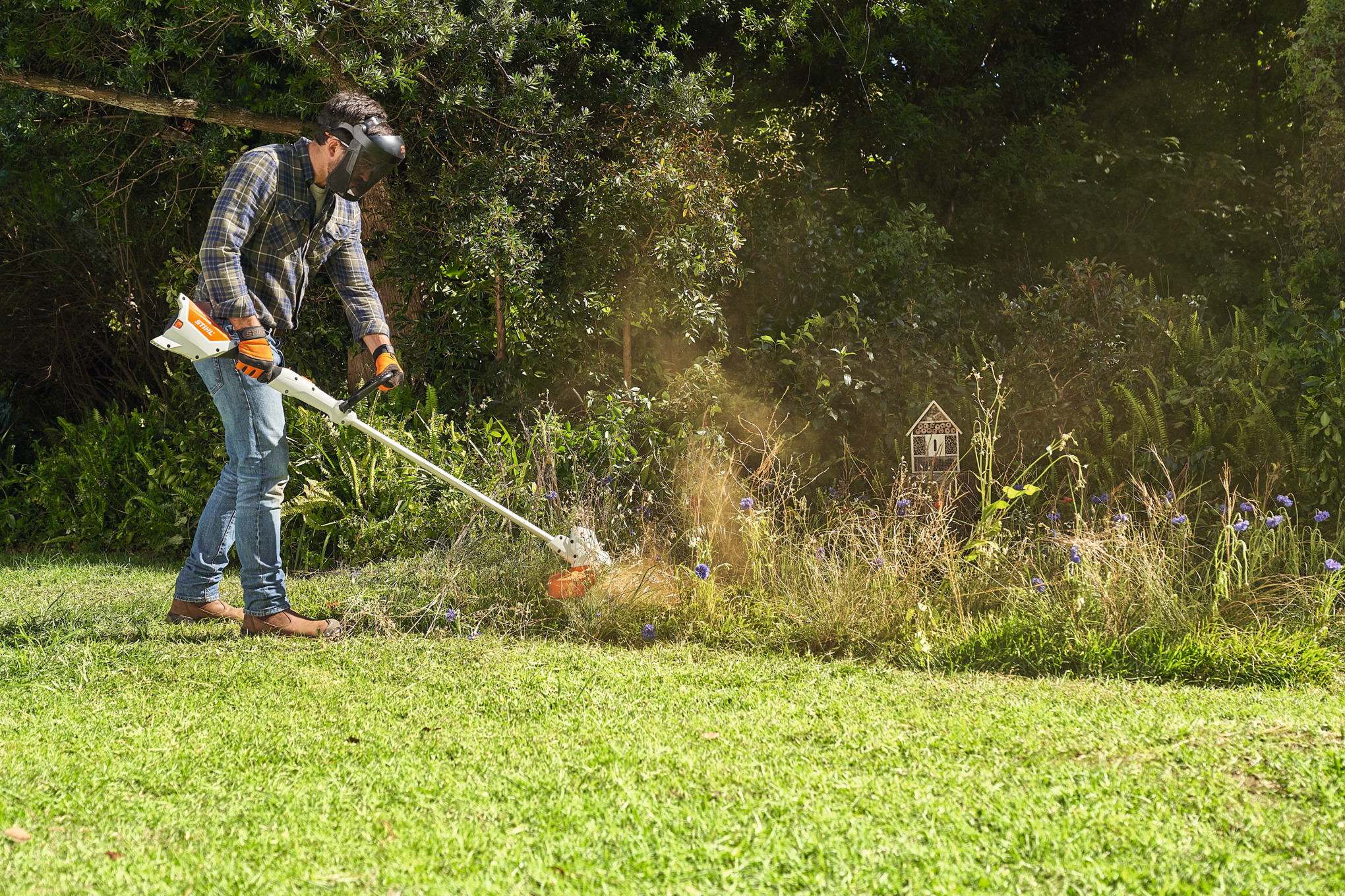 En man bär en STIHL trimmer över axeln