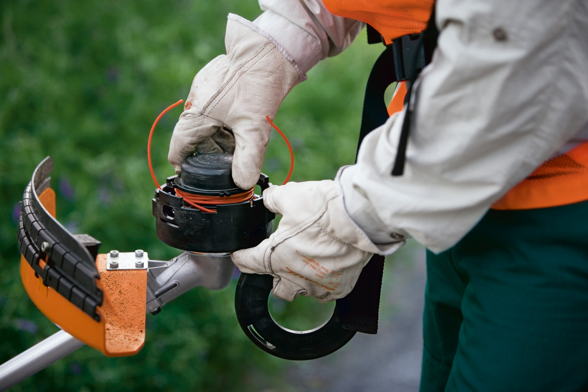 Person som bär skyddshandskar använder SuperCut-trimmerhuvudet med automatisk justering av skärtråden i en STIHL trimmer