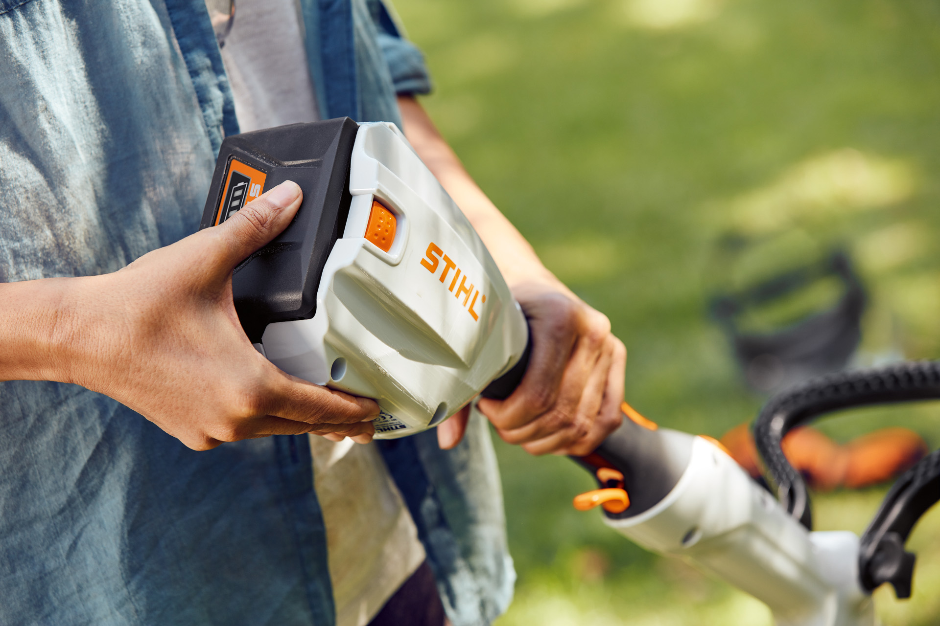 En person håller i STIHL FSA 56 batteridriven trimmer och för handen över batteriet.