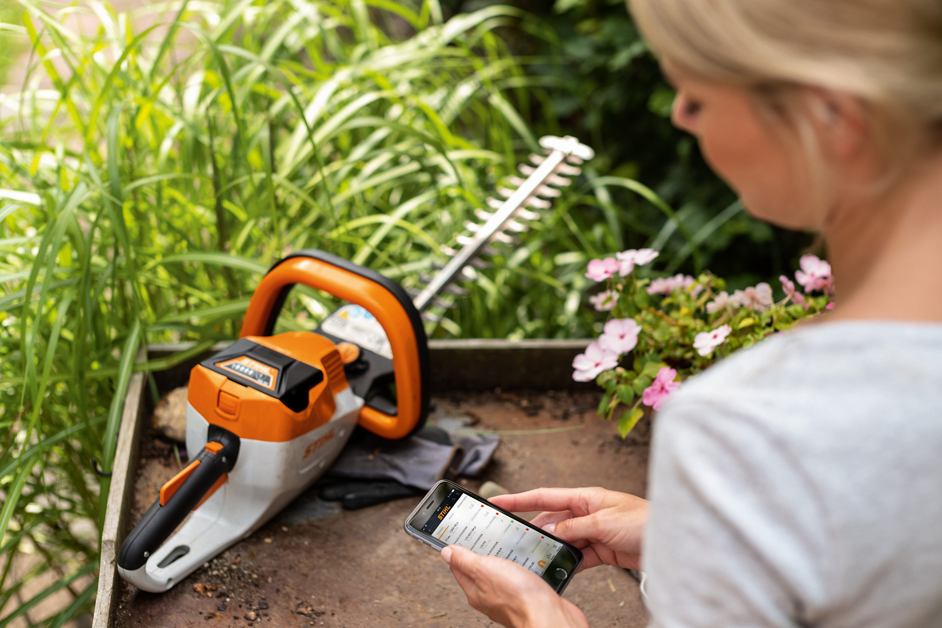 En kvinna registrerar sin STIHL häcksax via STIHL-appen på sin smartphone