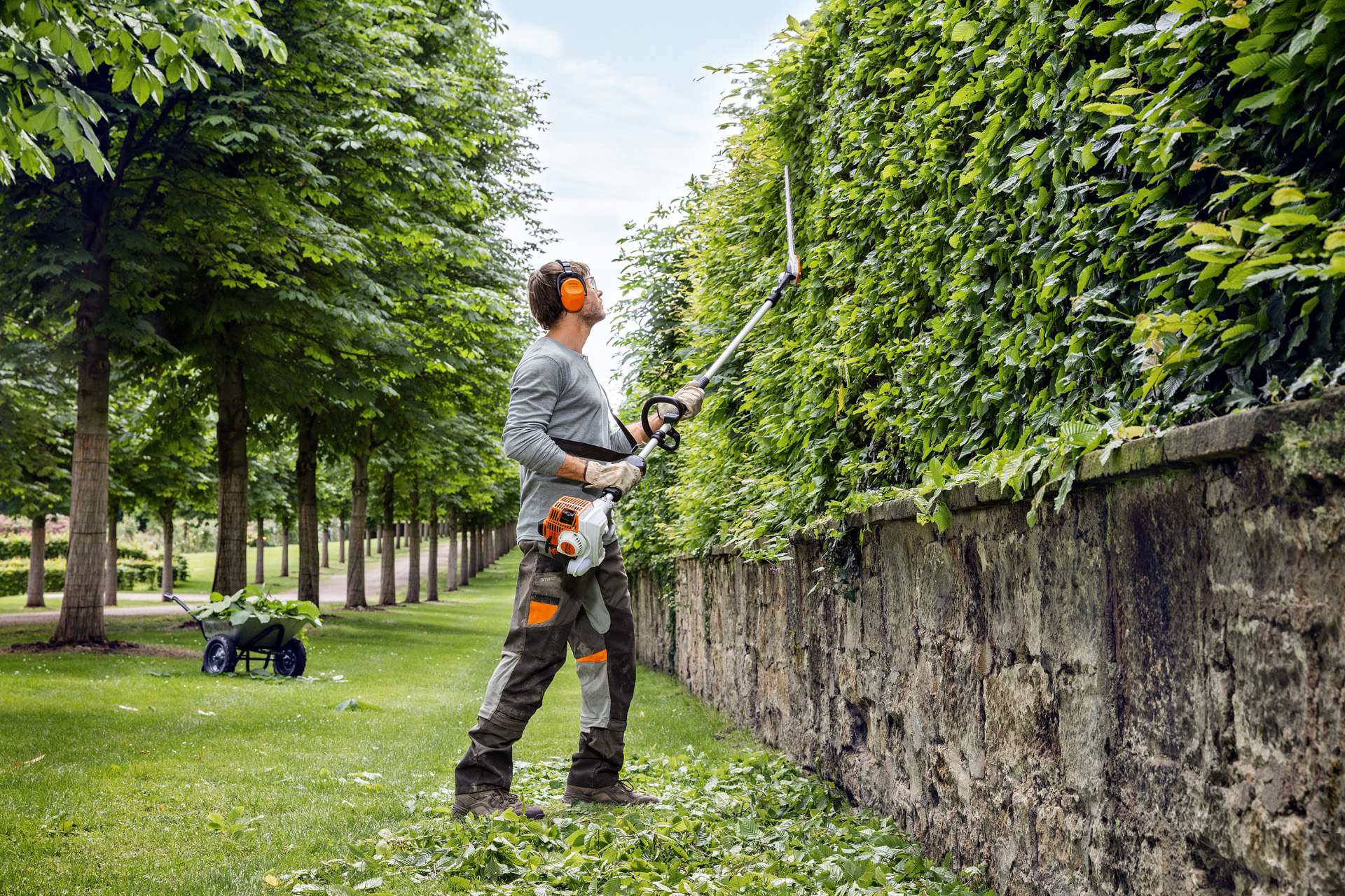 En man i skyddskläder gör en lateral, vertikal häckklippning med STIHL stånghäcksax HL 94