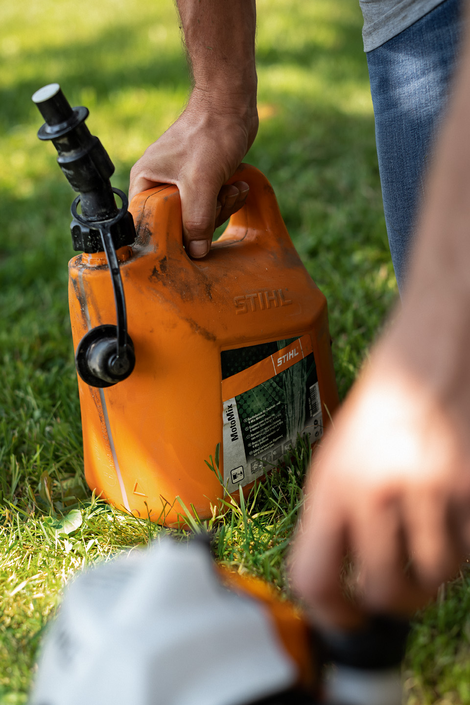 En man håller en behållare med bränsleblandningen STIHL MotoMix&nbsp;