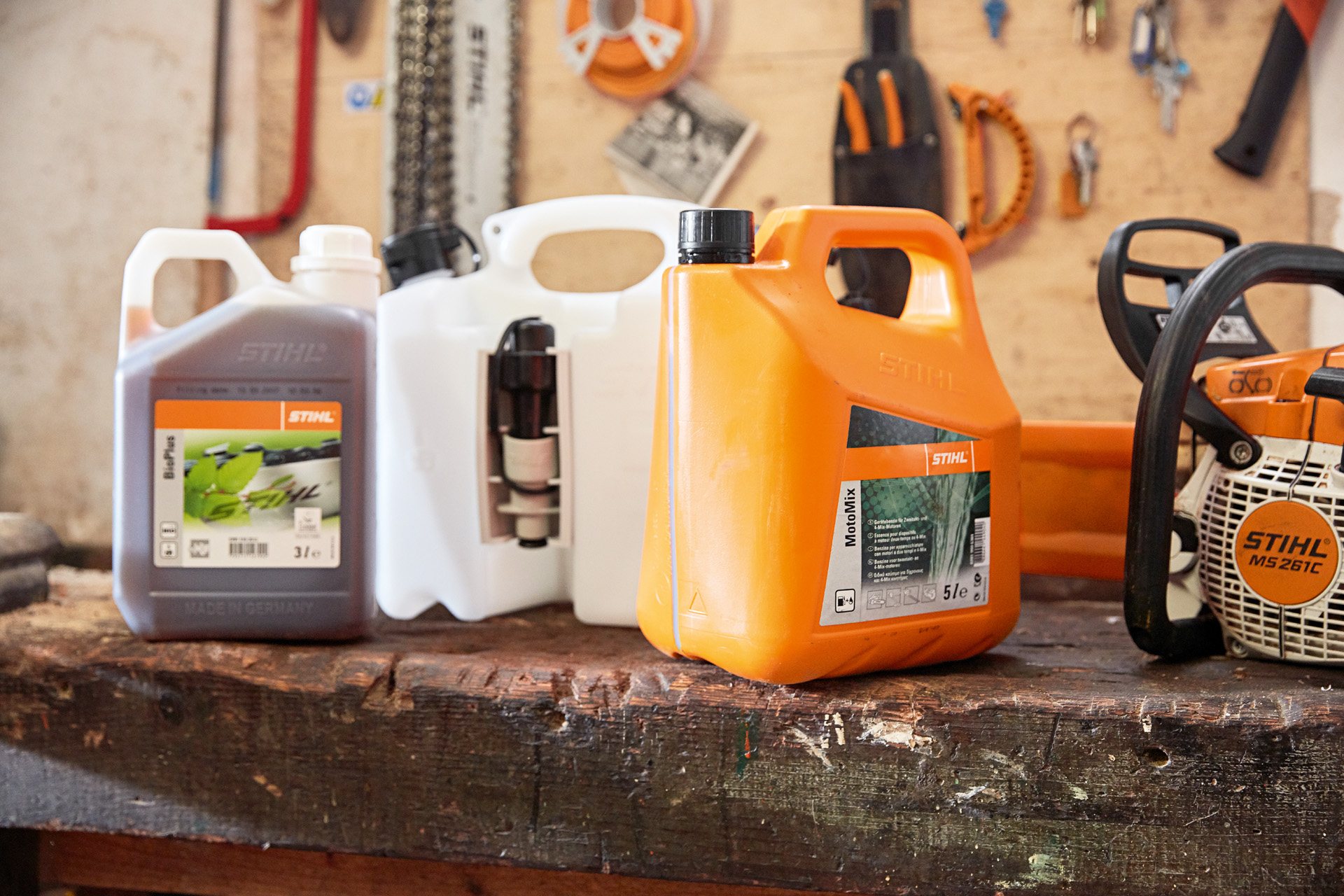 Kärl med STIHL MotoMix motorsågsblandning, olja och bensin och en STIHL MS 261 C bensindriven motorsåg i en verkstad