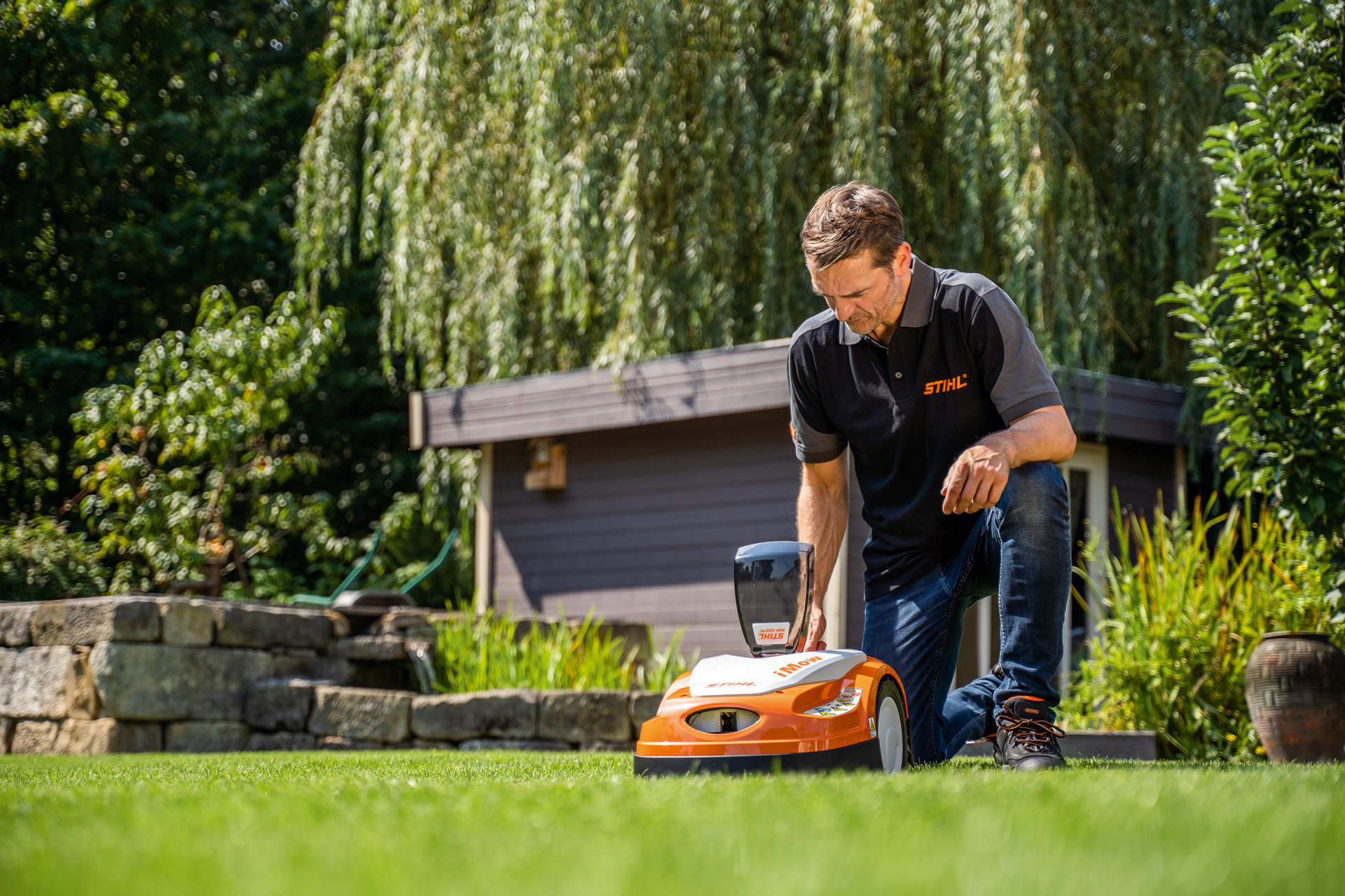 STIHL-återförsäljare programmerar klippningsplan för en STIHL iMOW robotgräsklippare i trädgården