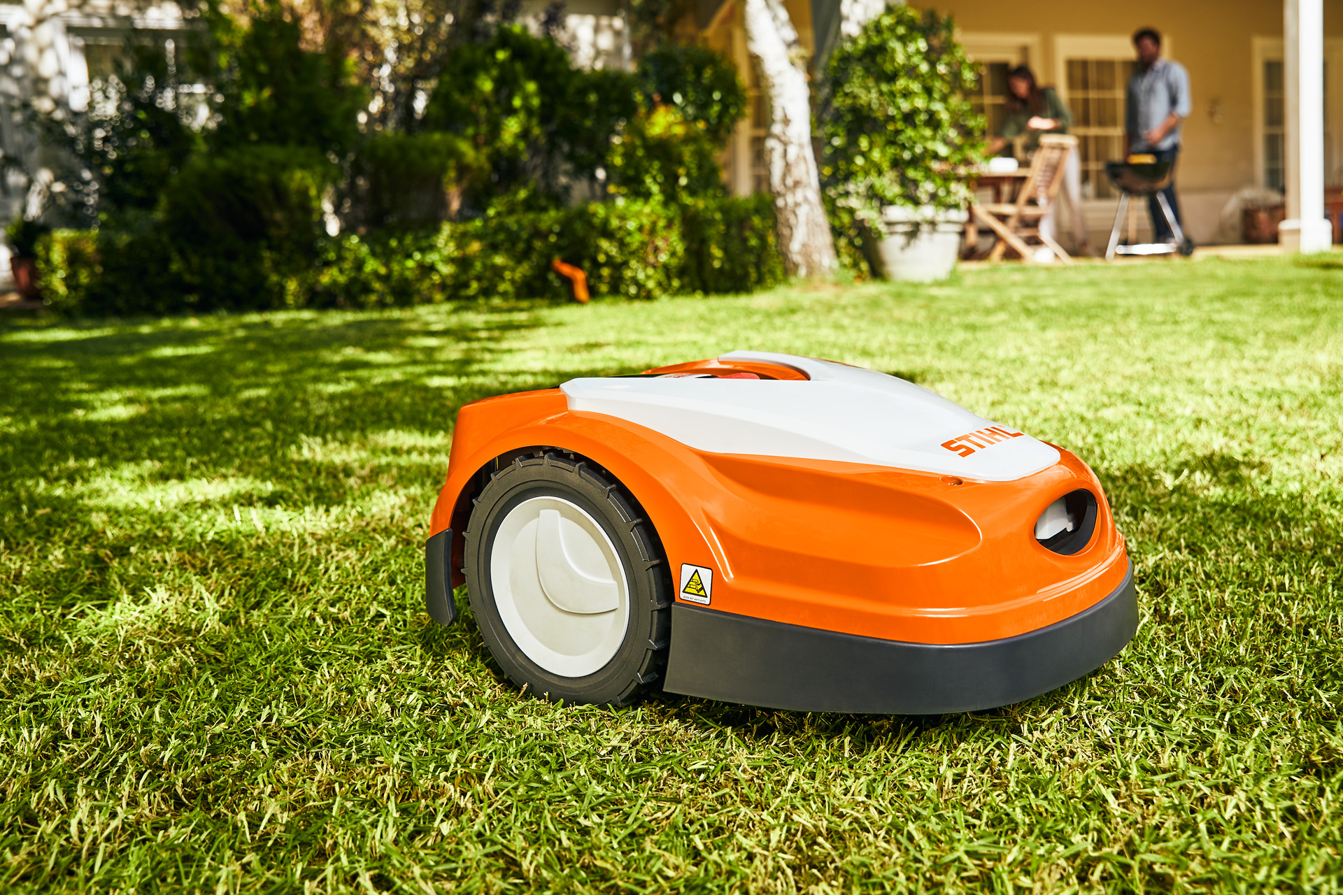 STIHL iMOW® RI 422 robotgräsklippare på en grön gräsmatta framför ett hus