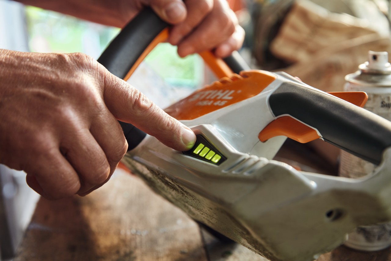 En person kontrollerar laddningsnivån på den sladdlösa häcksaxen STIHL HSA 45.