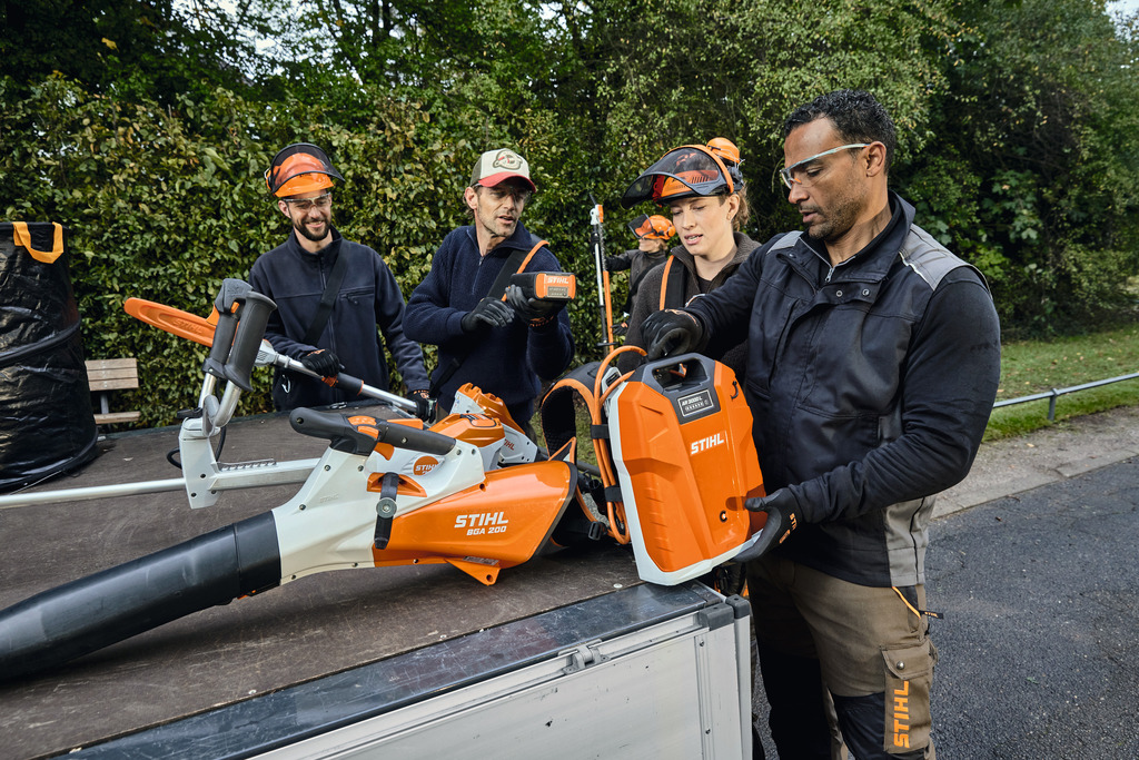 Ett team av landskapsarkitekter lastar av sin STIHL professionella batteridrivna utrustning från lastutrymmet på ett fordon.