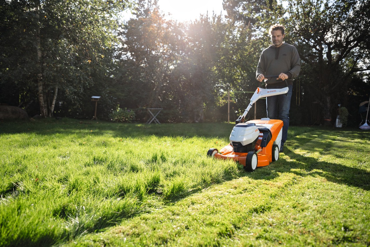 Ein Mann mäht mit einem Akku-Rasenmäher STIHL RMA 448 VC eine Rasenfläche